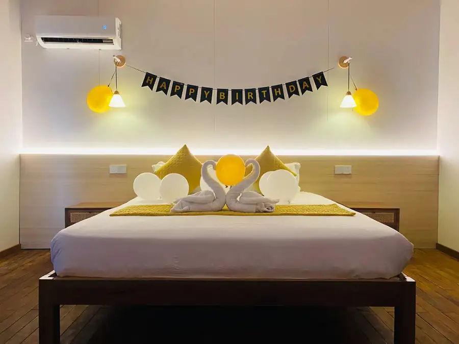 A celebratory bedroom at Sea Coral Resort near the Tun Sakaran Marine Park featuring a large bed decorated with swans and balloons, smooth wooden flooring, and aircon.