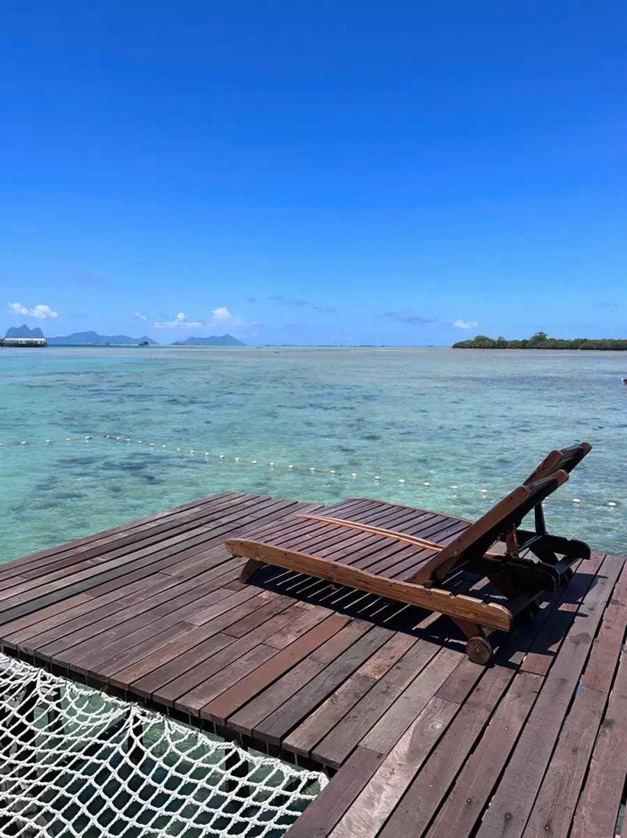 Private outdoor deck with sea views at Sea Coral Resort, featuring an overwater hammock net. Enjoy the cool tropical breeze and sweeping views of the vibrant Celebes Sea.
