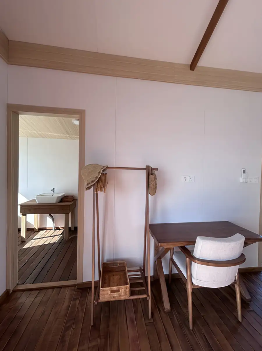 A practical workspace area at Sea Coral Resort in the Celebes Sea featuring a modern desk, wooden clothes rack, open access to the washbasin, rich mahogany style wooden floors, and air con.
